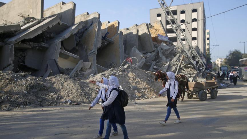 Des étudiants palestiniens passent devant les décombres d’un bâtiment détruit par les frappes aériennes israéliennes dans la ville de Gaza.