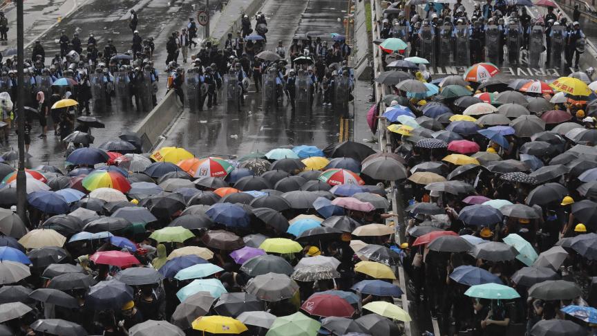 Les manifestants qui tiennent des parapluies font face à des policiers en tenue anti-émeute à Hong Kong ce lundi 1er juillet. Les manifestants tentent de bloquer l’accès à une cérémonie symboliquement importante marquant l’anniversaire du retour de l’ancienne colonie britannique en Chine.