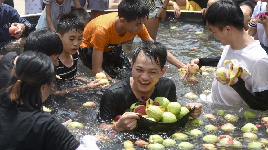 Des touristes mangent des fruits dans un seau de glace géant pour se rafraîchir lors d’une chaude journée dans une attraction en Chine.