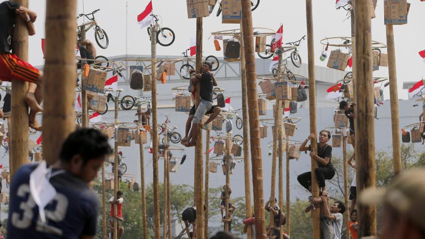 Les participants tentent d’atteindre les prix lors d’un concours d’escalade à mât graissé organisé dans le cadre des célébrations du Jour de l’indépendance à Ancol Beach à Jakarta, en Indonésie.