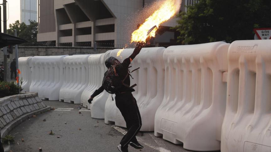 Un manifestant anti-gouvernement lance un cocktail Molotov lors d’une manifestation à Hong Kong. La violence a éclaté à nouveau et des milliers de partisans de la démocratie ont défilé dans le centre-ville au mépris d’une interdiction de police.