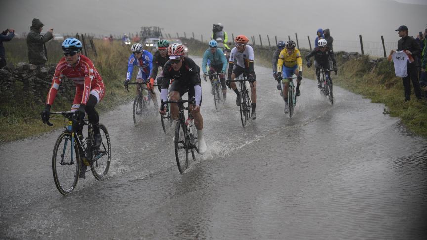 Coureurs traversant la pluie et une flaque d’eau géante sur la piste, lors de la course masculine aux Championnats du monde UCI de cyclisme sur route, à Harrogate au Royaume-Uni.