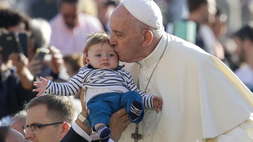 Le pape François embrasse un bébé alors qu’il arrive pour son audience générale hebdomadaire sur la place St. Pierre, au Vatican.
