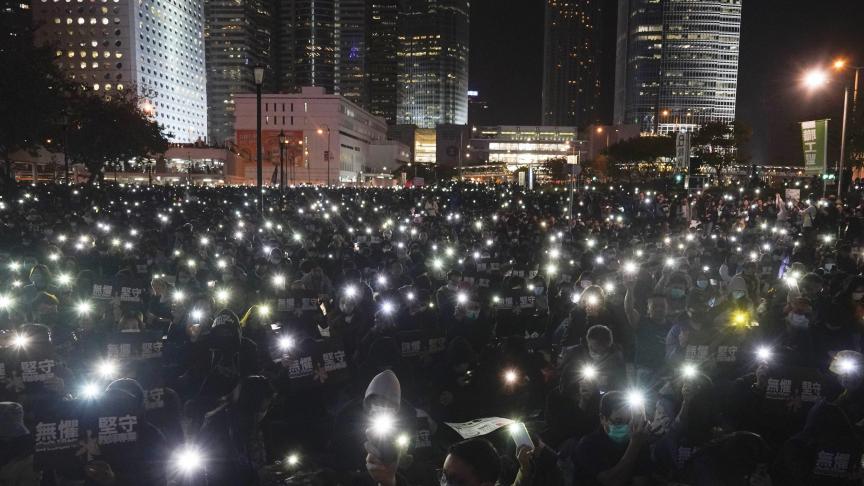 Les manifestants brandissent leur téléphone lors d’un rassemblement organisé par des travailleurs de l’éducation à Hong Kong.