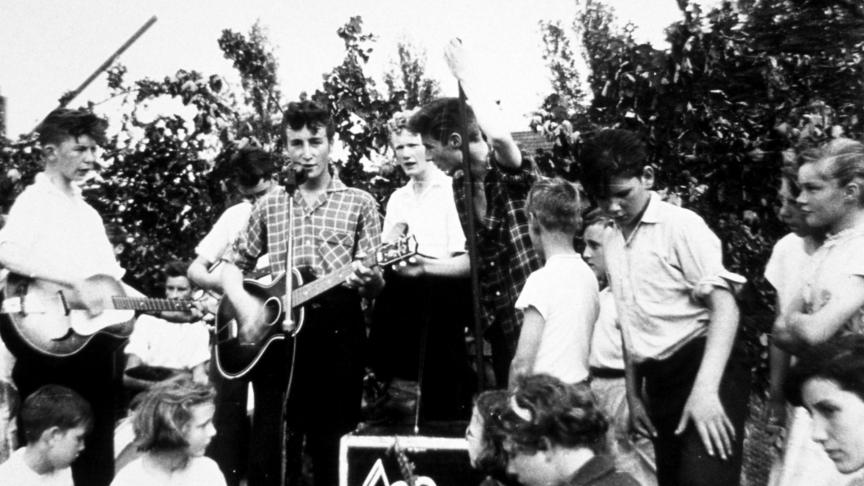 John Lennon, chemise à carreaux, structure un petit groupe en 1957
: «
The Quarrymen
»