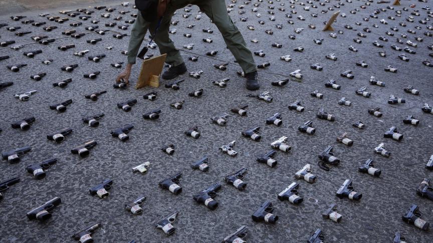 Un policier panaméen installe des armes de poing sur le terrain pour les exposer à la presse avant de les détruire à Panama City. Selon la police du Panama, ils ont saisi et détruit 589 armes durant les six derniers mois.