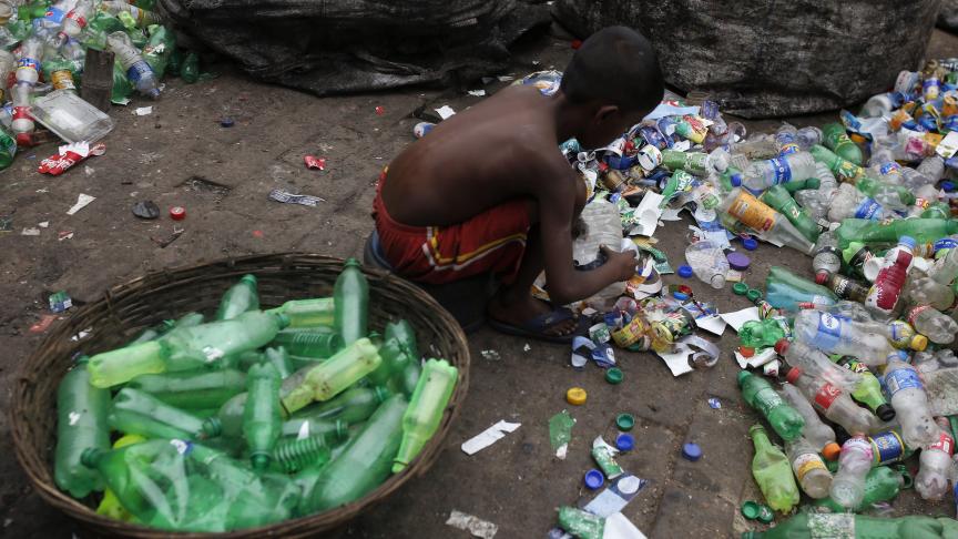 Un enfant trie des bouteilles en plastique dans une usine de recyclage à Dhaka au Bangladesh. Tous les jours après l’école, il aide sa grand-mère dans cette usine.