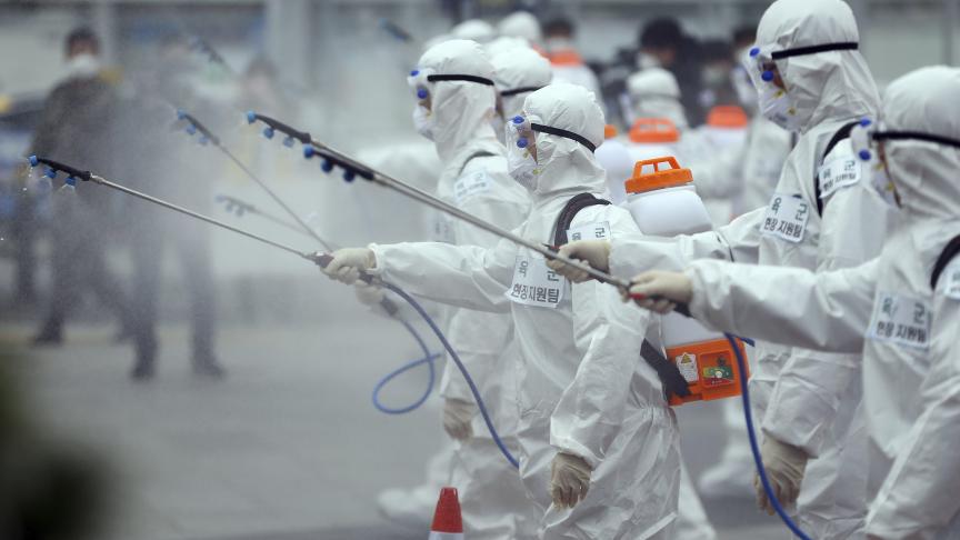 Soldats de l’armée portant des combinaisons de protection en train de pulvériser du désinfectant pour empêcher la propagation du coronavirus à la gare de Dongdaegu en Corée du Sud.