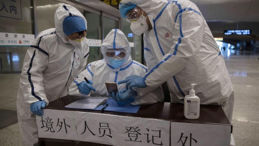 Des travailleurs de la santé vérifient les informations d’un passager arrivant de Beijing à la gare de Wuhan, dans la province chinoise centrale de Hubei.