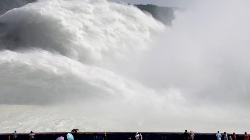 Des touristes regardent les énormes vagues venues d’un réservoir d’eau qui se vide en Chine.
