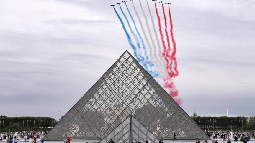 L’équipe de vol acrobatique d’élite française réalise une exposition aérienne du drapeau national français au-dessus de la pyramide du Louvre, lors de la cérémonie militaire annuelle du 14 juillet.