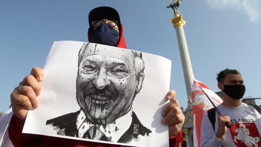 Un manifestant biélorusse tient une pancarte du président décrié Alexander Lukashenko.