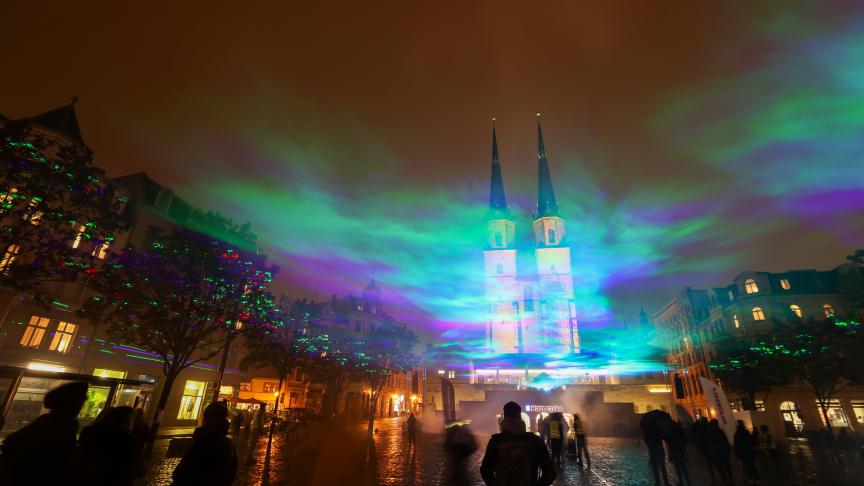 Les passants observent des aurores artificiellement générées à l’aide de faisceaux laser et de brouillard à Halle, en Allemagne.