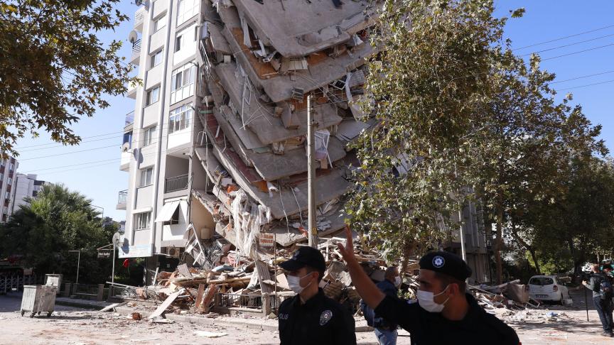 Des agents de sécurité marchent près des débris d’un bâtiment effondré à Izmir, en Turquie, suite à un puissant tremblement de terre qui a frappé la côte turque de la mer Égée.