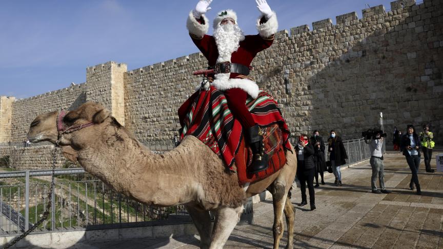 Issa Kassissieh, mieux connu sous le nom de Père Noël de Jérusalem, chevauche un chameau à l’extérieur de la vieille ville de Jérusalem.