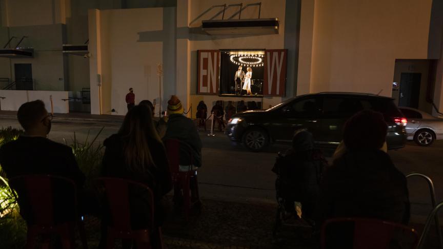 Des gens regardent les acteurs jouer Seven Deadly Sins derrière la vitrine d'un magasin vacant sur Lincoln Road à Miami Beach.