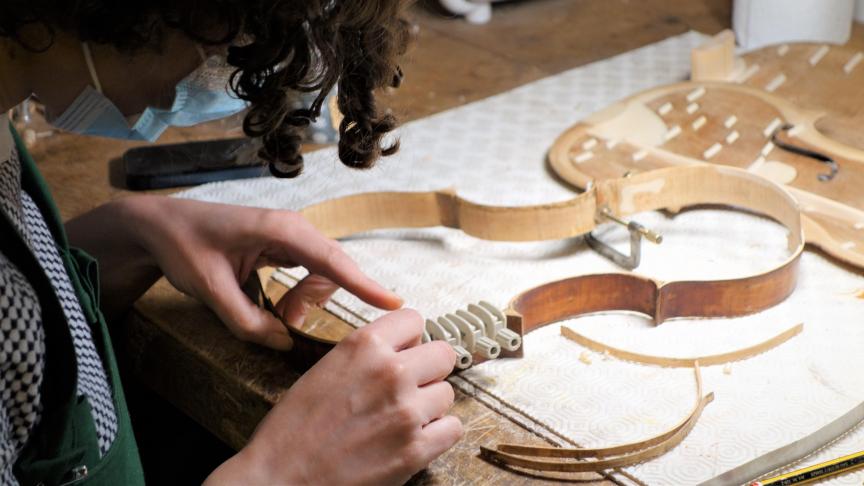 Verena Behrendt, luthière de la Maison Bernard, forme la couronne d’éclisses qui bordera l’instrument. © Maël Duchemin