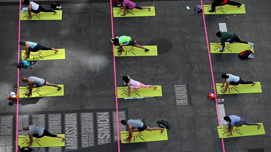 Des New-Yorkais participent au « Mind Over Madness Yoga » pour célébrer le solstice d’été à Times Square.