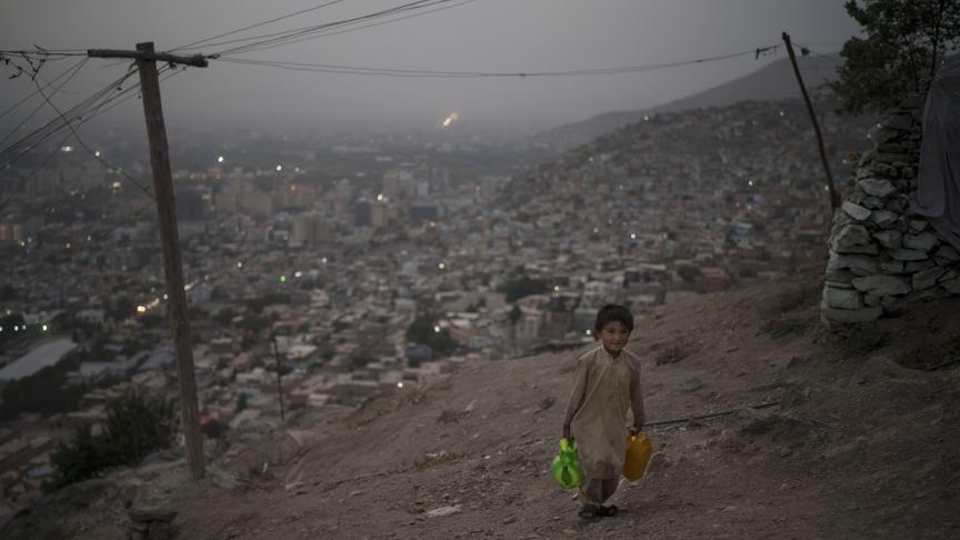Un garçon transporte de l’eau jusqu’à sa maison au sommet d’une colline à Kaboul, en Afghanistan.