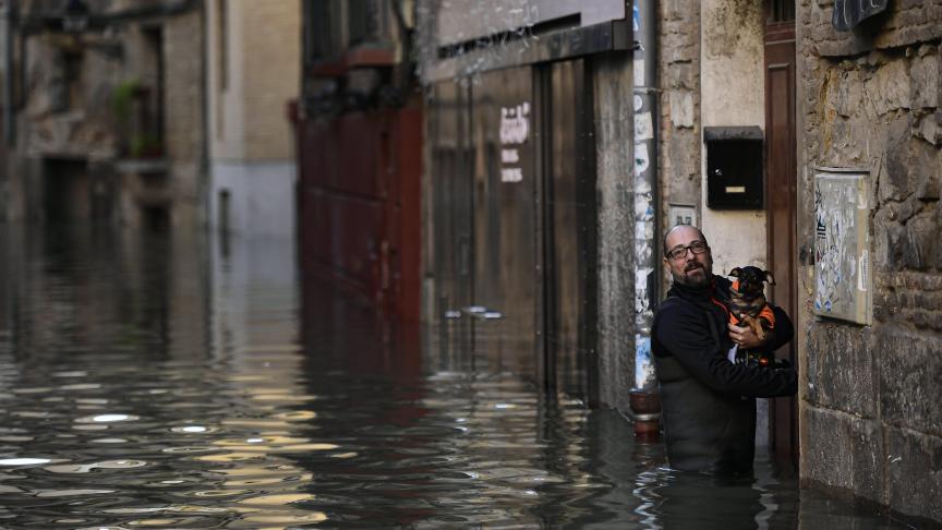 Un homme porte son chien, après les inondations qui ont eu lieu dans le nord de l’Espagne.