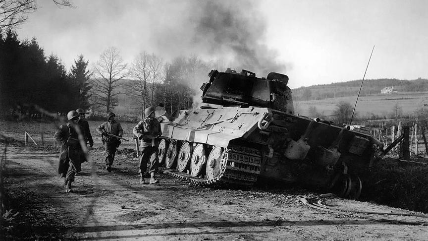 Des G.I. américains passent à côté d’un panzer allemand détruit pour cause de panne sèche…