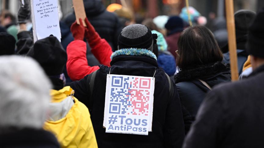 Un manifestant marche avec une pancarte indiquant Tous anti-pass lors d'une manifestation pour protester contre le pass sanitaire et les vaccins Covid-19 à Nantes, dans l'ouest de la France, le 15 janvier 2022.