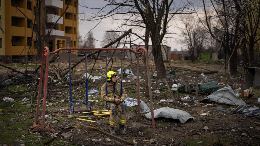 Un pompier est assis sur une balançoire à côté d’un bâtiment détruit par une bombe russe à Chernihiv.