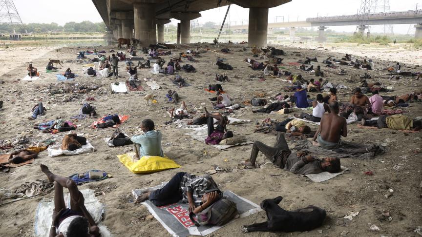 Des sans-abri dorment à l’ombre d’un pont par une chaude journée à New Delhi.