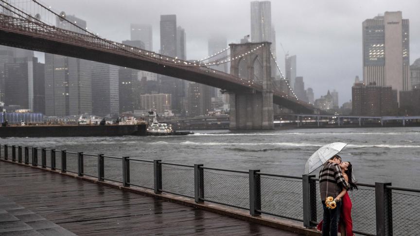 Un couple pose pour des photos devant le pont de Brooklyn un jour pluvieux.