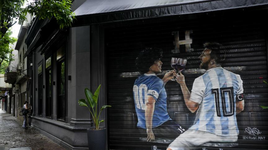 Des images des stars du football Diego Maradona, à gauche, et Lionel Messi dessinées par l'artiste péruvien Mario Abad Causi sont présentées à la fenêtre fermée du restaurant Hierro à Buenos Aires, en Argentine.