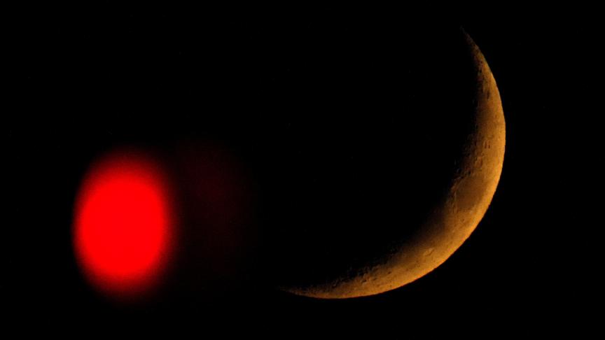 Le croissant de lune se couche au-delà d'un feu rouge à Overland Park, Kan.