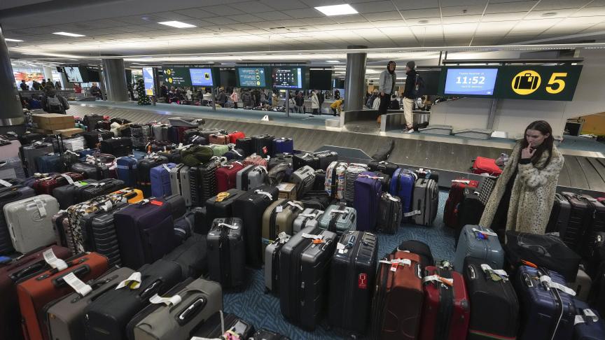 Une femme cherche ses bagages à l'aéroport international de Vancouver après une tempête de neige qui a paralysé les opérations, entraînant des annulations et des retards importants, à Richmond, en Colombie-Britannique, le mardi 20 décembre 2022.