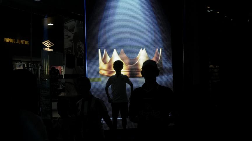 Des visiteurs se tiennent devant une couronne affichée sur un écran de télévision à la boutique de souvenirs du stade Vila Belmiro, domicile du club de football Santos FC, à Santos, au Brésil, jeudi 29 décembre 2022.