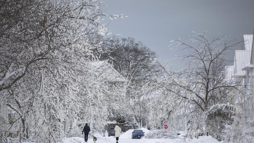 Des personnes marchent le long d'une rue couverte de glace à Fort Erie, en Ontario, le mardi 27 décembre 2022, après une tempête hivernale qui a balayé une grande partie de l'Ontario.