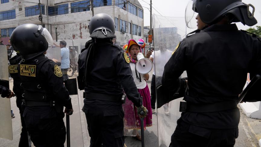 Une manifestante anti-gouvernemental défie la police entourant l'Université San Marcos à Lima, au Pérou.