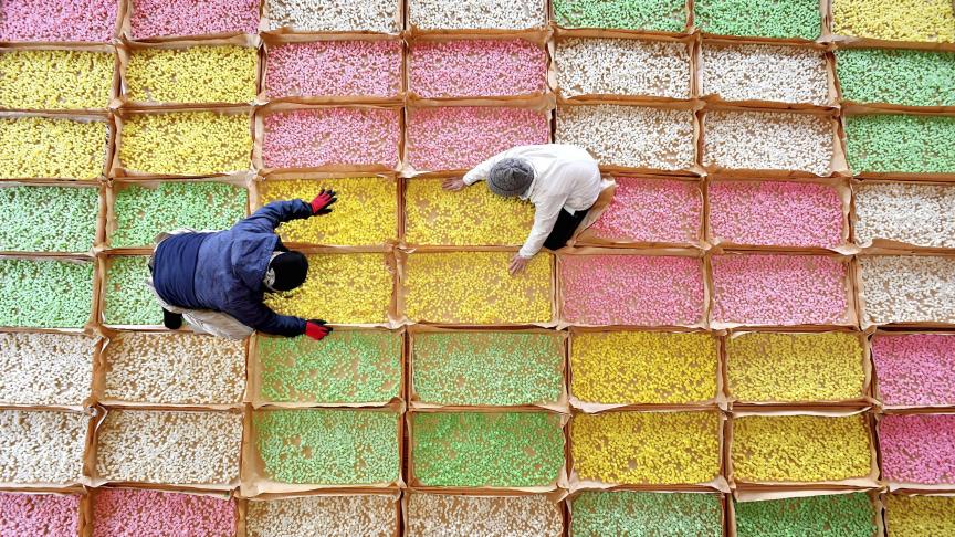 Les agriculteurs trient des craquelins carrés d'un centimètre, faits de riz gluant, en fonction de couleurs telles que le rose, le jaune, le vert clair et le blanc cassé sur le lieu de travail de Shika, préfecture d'Ishikawa, au Japon.