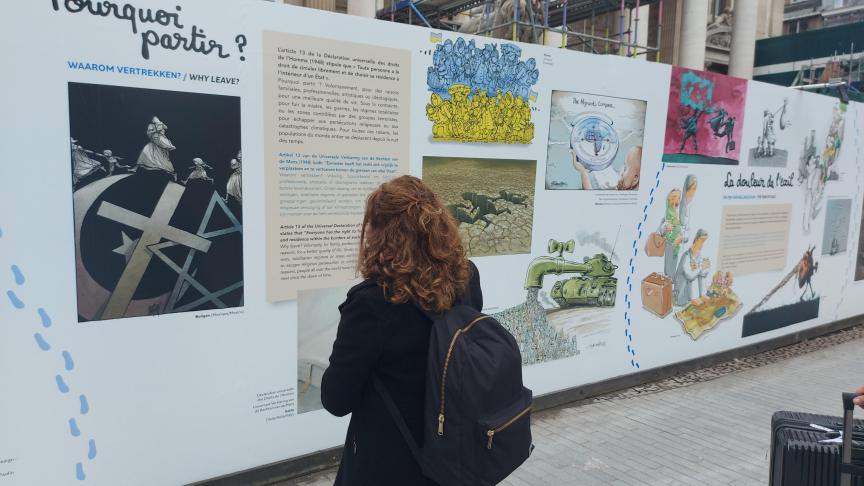 Une passante venue des Etats-Unis s’intéresse à la fresque de Cartooning for peace sur le chantier de la Bourse à Bruxelles.