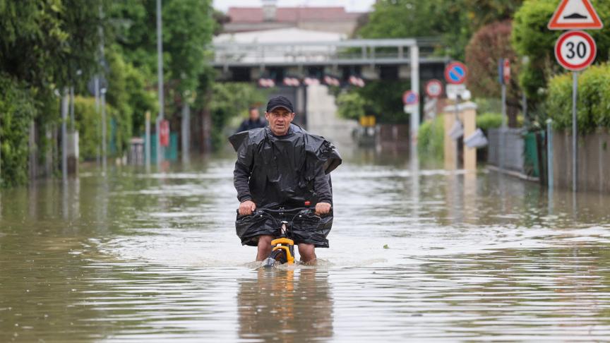 Un homme roule à vélo dans le nord de l’Italie, le 19 mai 2023, après des pluies intenses.
