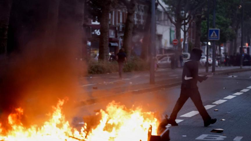 Un homme passe devant un feu de joie lors de manifestations à Lille, dans le nord de la France, le 29 juin 2023, deux jours après qu’un adolescent a été abattu lors d’un contrôle routier dans la banlieue parisienne de Nanterre. 