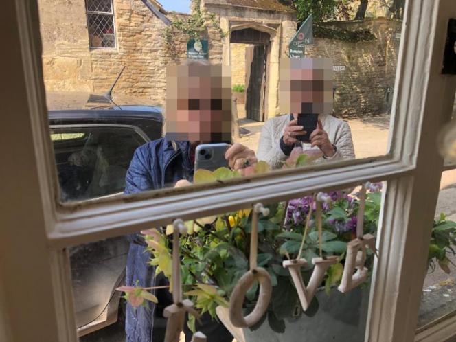 Deux touristes tiennent leur téléphone pour photographier la fenêtre d'un villageois. - Compte Twitter @markchristie