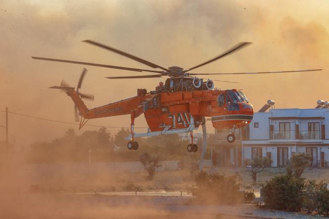 Un hélicoptère de lutte contre les incendies remplit l’eau d’une piscine, alors qu’un feu de forêt brûle dans le village de Gennadi, sur l’île de Rhodes, en Grèce, le 25 juillet 2023.