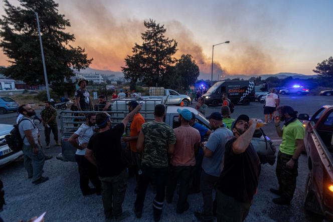 Des bénévoles se rafraîchissent avant de s’attaquer à un incendie de forêt dans le village de Gennadi, sur l’île de Rhodes, en Grèce, le 25 juillet 2023.