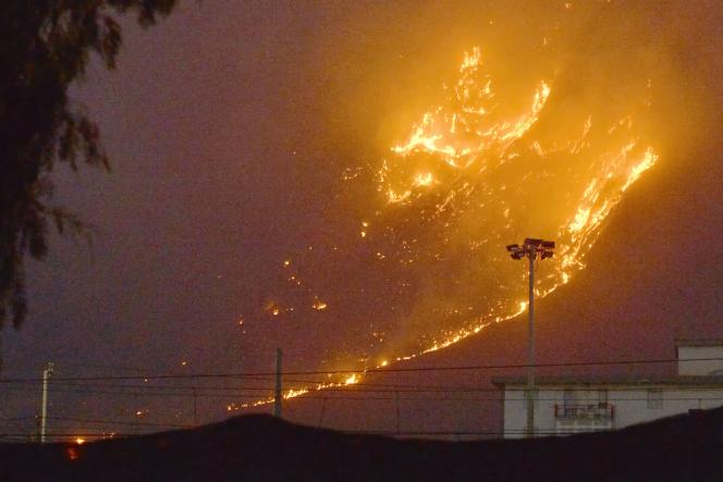 Cette photo obtenue de l’agence de presse italienne Ansa montre un vaste incendie se propageant sur les collines de la région de Monte Grifone et de la ville de Ciaculli autour de Palerme, en Sicile, le 25 juillet 2023, avec des flammes menaçant les maisons voisines.